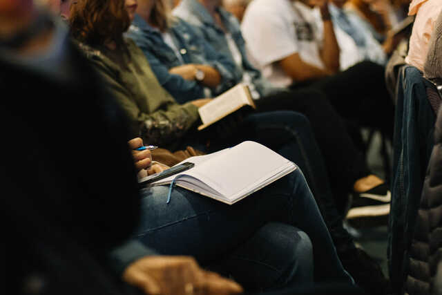 Individuals taking notes at a speaking engagement