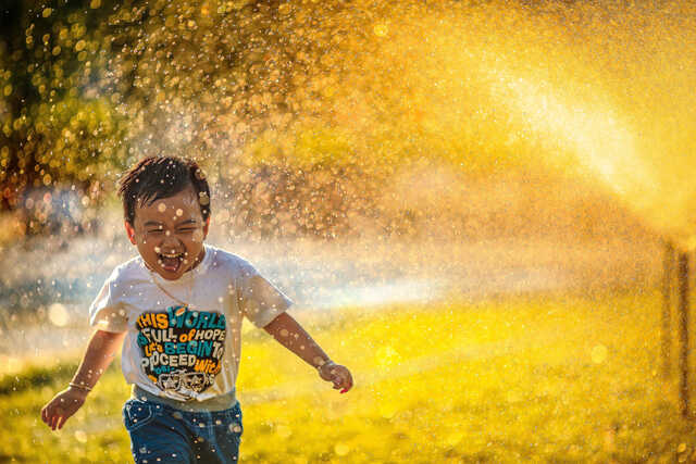 kid playing in sprinklers