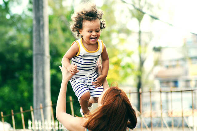 mother tossing young child in the air