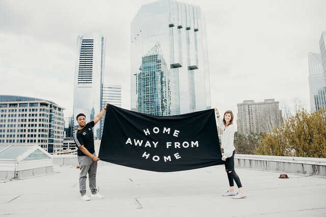 college students holding up home away from home sign