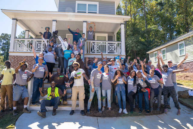 Volunteers pose on the porch of a habitat for humanity house