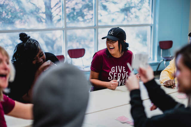 girl playing cards and laughing while serving people at a homeless shelter