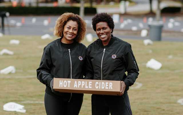 volunteers handing out apple cider on the lawn