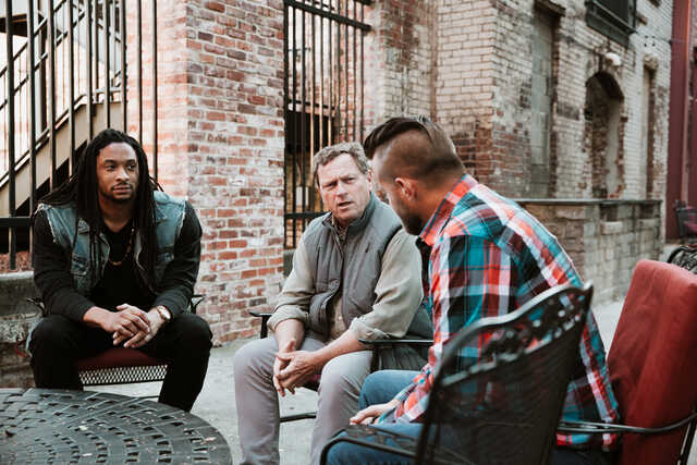 diverse group of men meeting outside on a patio